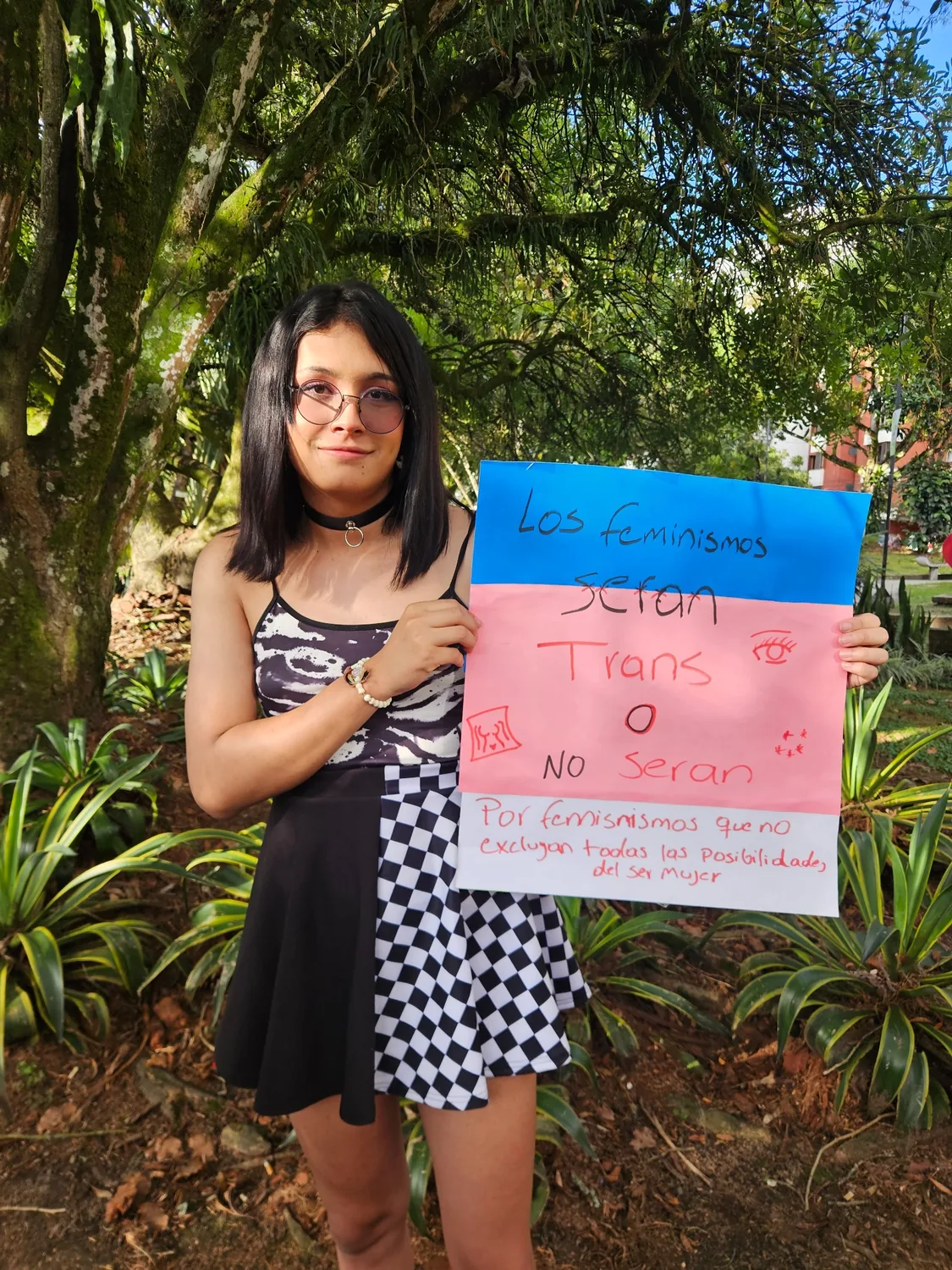 Persona sosteniendo un cartel con la bandera trans
